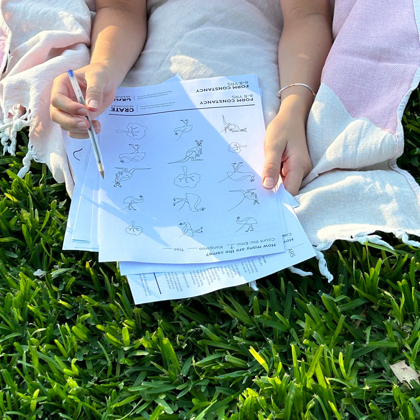pair of girls hands holding a worksheet counting the emus and kangaroos that are upside down and sideways